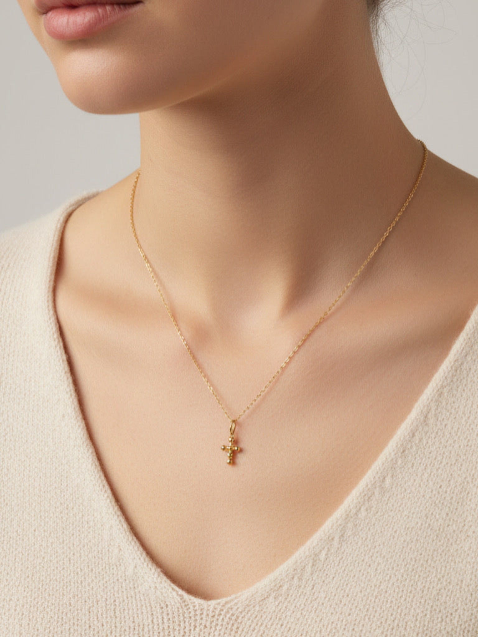 Gold necklace with a small cross pendant on a neutral background