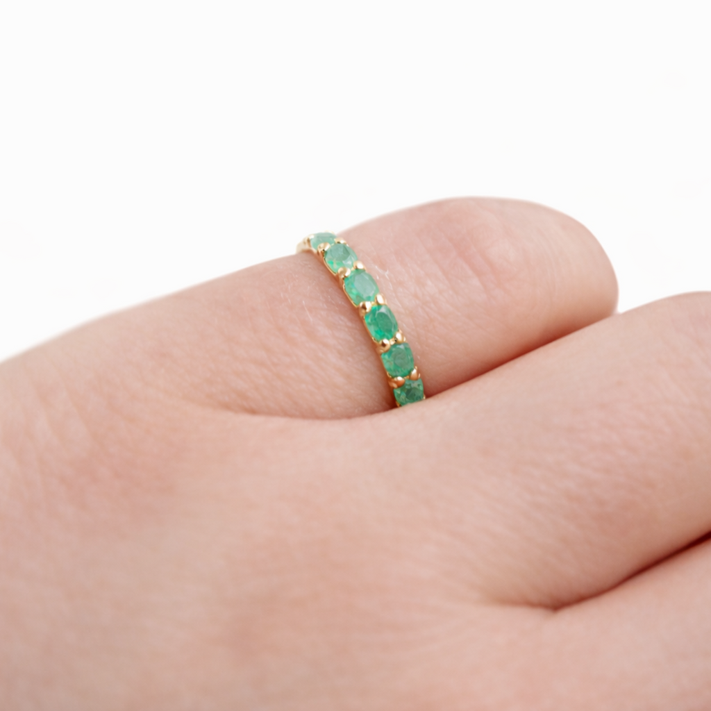 Green gemstone ring on a finger against a white background